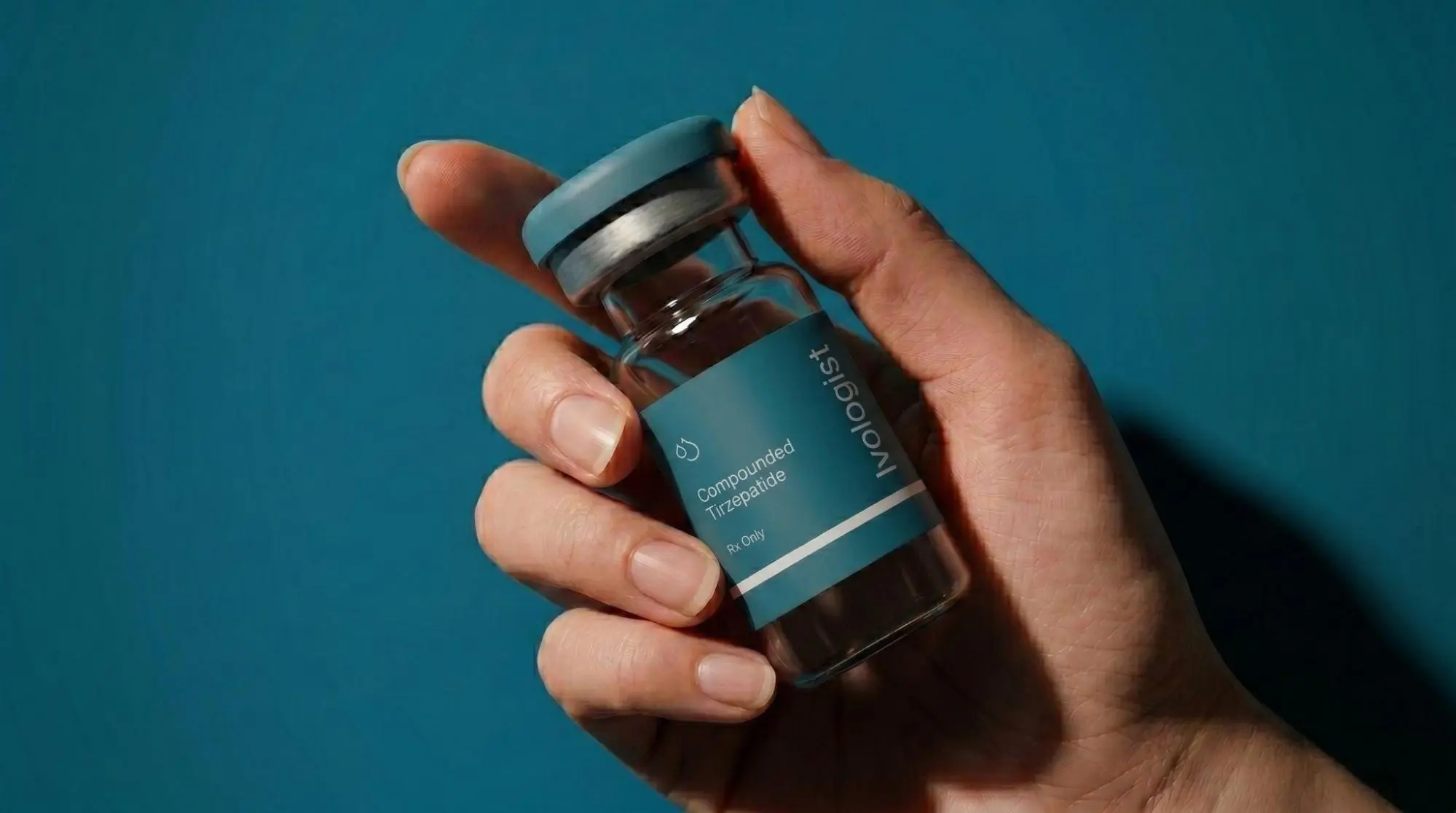 Hand holding a vial of compounded tirzepatide